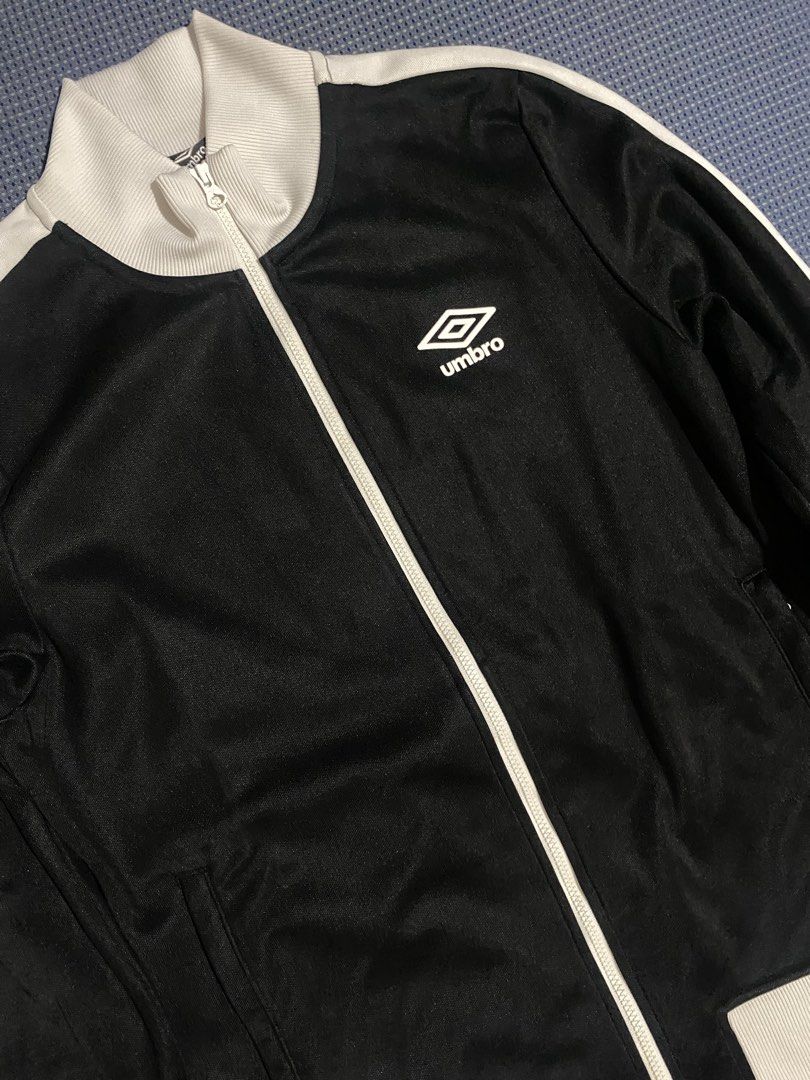 Umbro Black & White Track Jacket (Category: Coats, Jackets and Outerwear) located in Iloilo. Submitted by astaaa777 (Listing ID 1463640839, Image 3). Description: - Classic Umbro track jacket - Color: Black with white stripes on sleeves and collar - Full zip front closure - Two side pockets - Umbro logo on chest - Large Umbro graphic on back - Ribbed cuffs and hem.