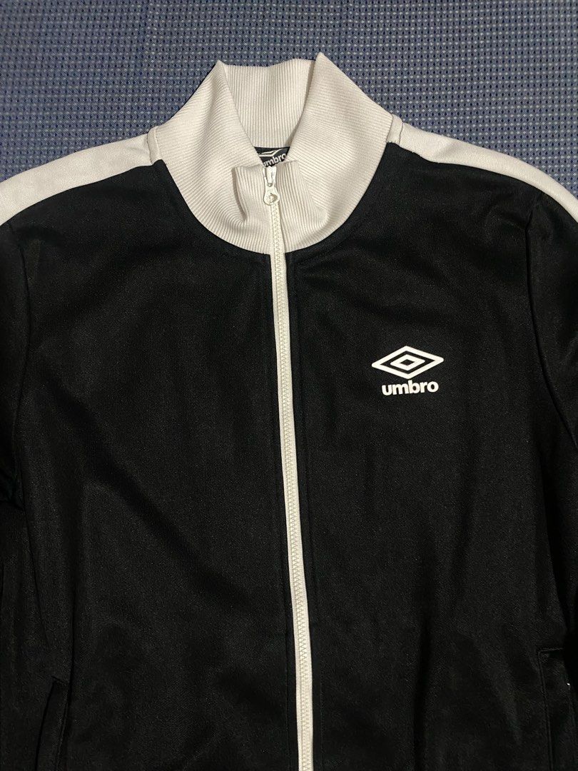 Umbro Black & White Track Jacket (Category: Coats, Jackets and Outerwear) located in Iloilo. Submitted by astaaa777 (Listing ID 1463640839, Image 2). Description: - Classic Umbro track jacket - Color: Black with white stripes on sleeves and collar - Full zip front closure - Two side pockets - Umbro logo on chest - Large Umbro graphic on back - Ribbed cuffs and hem.