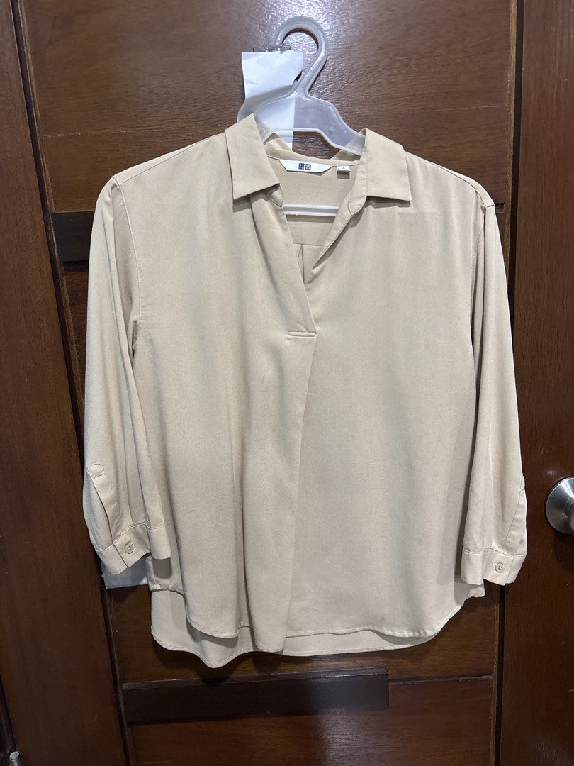 Uniqlo Beige Collared Long Sleeve Blouse Size S (With Marks) (Category: Longsleeves) located in Mandaluyong City. Submitted by clothescarousel (Listing ID 1463670192, Image 1). Description: - Uniqlo collared blouse - Beige color - Long sleeves with button cuffs - Fabric has a slight sheen - Small mark on the front (see close-up photo) - Versatile for casual or work wear.