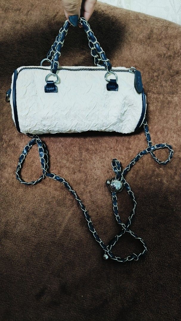 White Micro Barrel Handbag with Chain Strap (Category: Shoulder Bags) located in Manila. Submitted by serenitycarlylle (Listing ID 1463726211, Image 2). Description: - Unique white barrel-shaped handbag - Textured material for added detail - Stylish navy blue trim and chain strap - Secure zipper closure - Versatile carrying options: top handles or long chain strap for crossbody wear - Adorable small metal charm on the strap.
