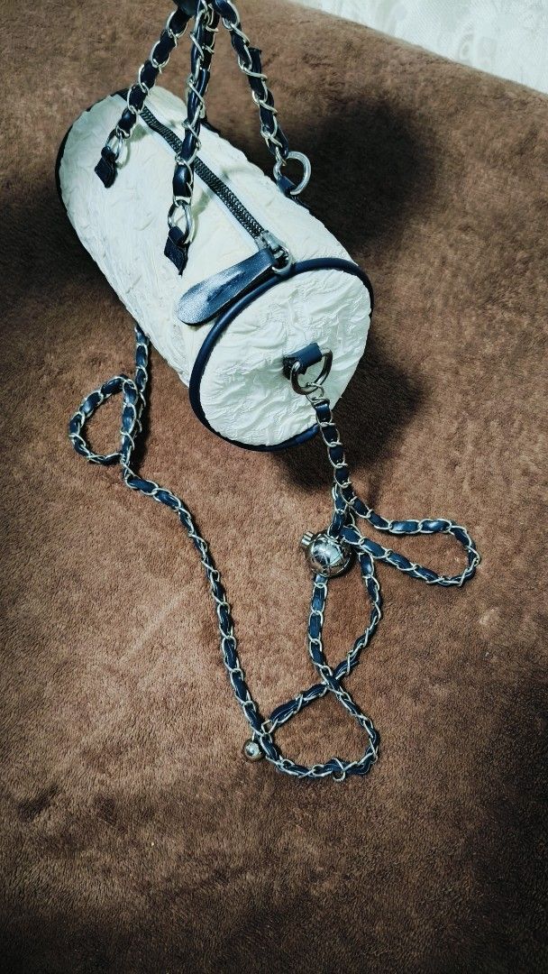White Micro Barrel Handbag with Chain Strap (Category: Shoulder Bags) located in Manila. Submitted by serenitycarlylle (Listing ID 1463726211, Image 3). Description: - Unique white barrel-shaped handbag - Textured material for added detail - Stylish navy blue trim and chain strap - Secure zipper closure - Versatile carrying options: top handles or long chain strap for crossbody wear - Adorable small metal charm on the strap.