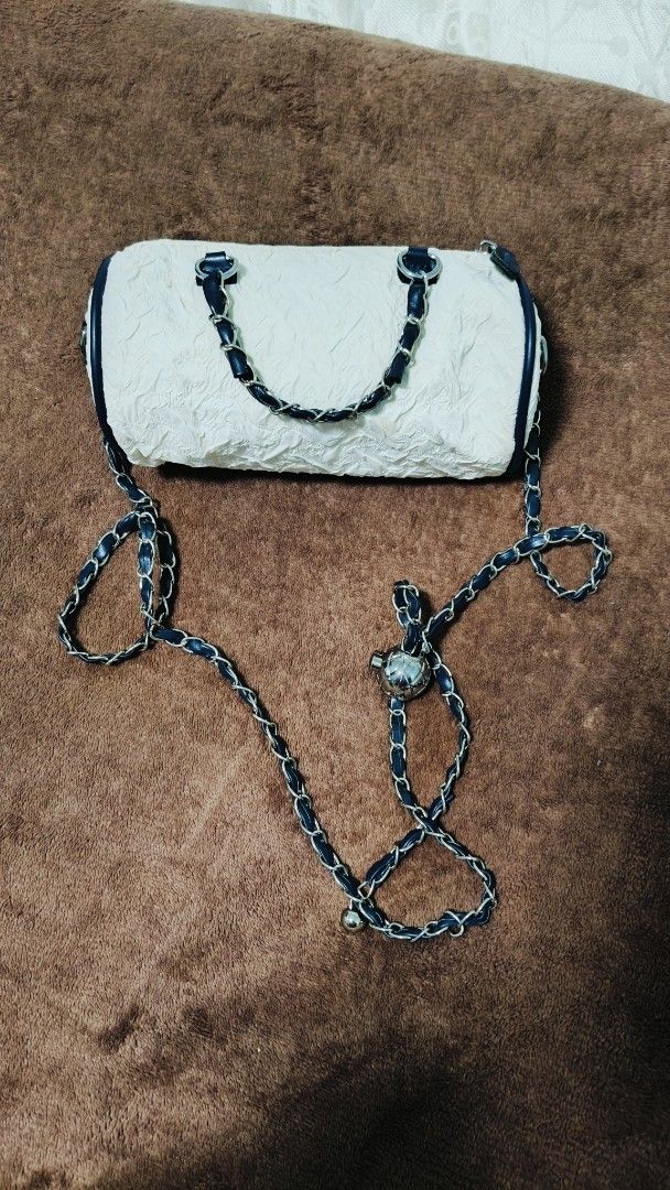 White Micro Barrel Handbag with Chain Strap (Category: Shoulder Bags) located in Manila. Submitted by serenitycarlylle (Listing ID 1463726211, Image 1). Description: - Unique white barrel-shaped handbag - Textured material for added detail - Stylish navy blue trim and chain strap - Secure zipper closure - Versatile carrying options: top handles or long chain strap for crossbody wear - Adorable small metal charm on the strap.