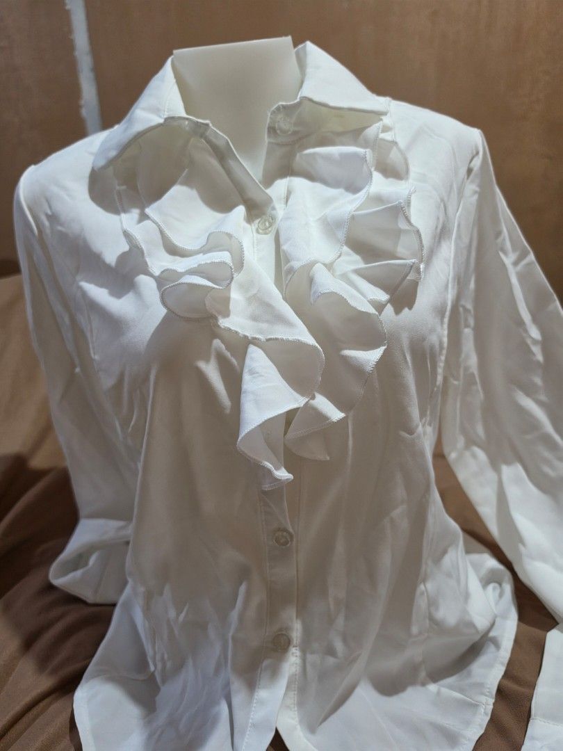 White Ruffled Blouse with Buttons (Category: Blouses) located in Malabon City. Submitted by lpzangie (Listing ID 1463706743, Image 1). Description: - White long-sleeved blouse - Size 5XL (Fit to Medium to Semi XL) - Ruffles down the front - Button closures - Decorative buttons on cuffs - Lightweight and flowy material - With Extra Button.