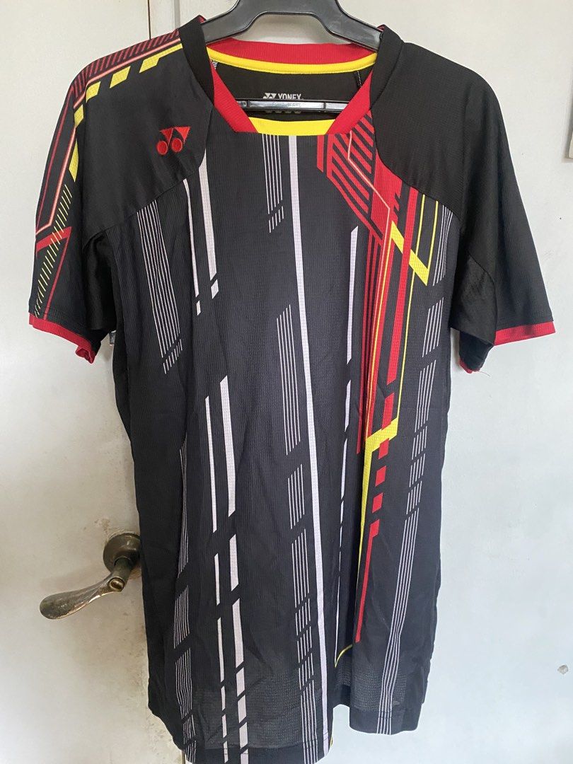 Yonex Badminton Jersey Black Red Yellow (Category: Activewear) located in Manila. Submitted by antonvarga38504 (Listing ID 1463596391, Image 1). Description: - Yonex Badminton Jersey - Color: Black with dynamic red and yellow graphic print - Features: Short sleeves with red trim - Material: Comfortable and breathable fabric - Ideal for: Playing sports or casual wear.