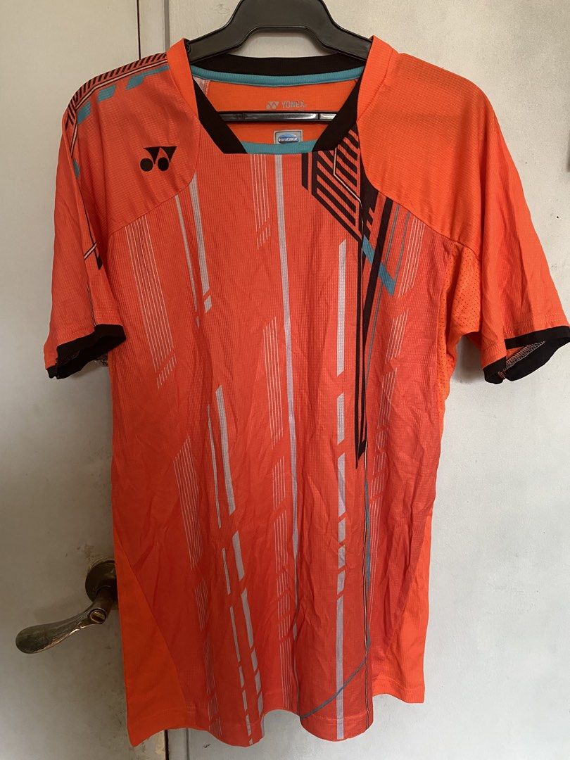 Yonex Orange Badminton Jersey (Category: Activewear) located in Manila. Submitted by antonvarga38504 (Listing ID 1463595936, Image 1). Description: - Orange Yonex sports jersey - Features a graphic print with white and light blue lines - Short sleeves with black trim - Comfortable and breathable material - Ideal for badminton and other sports.