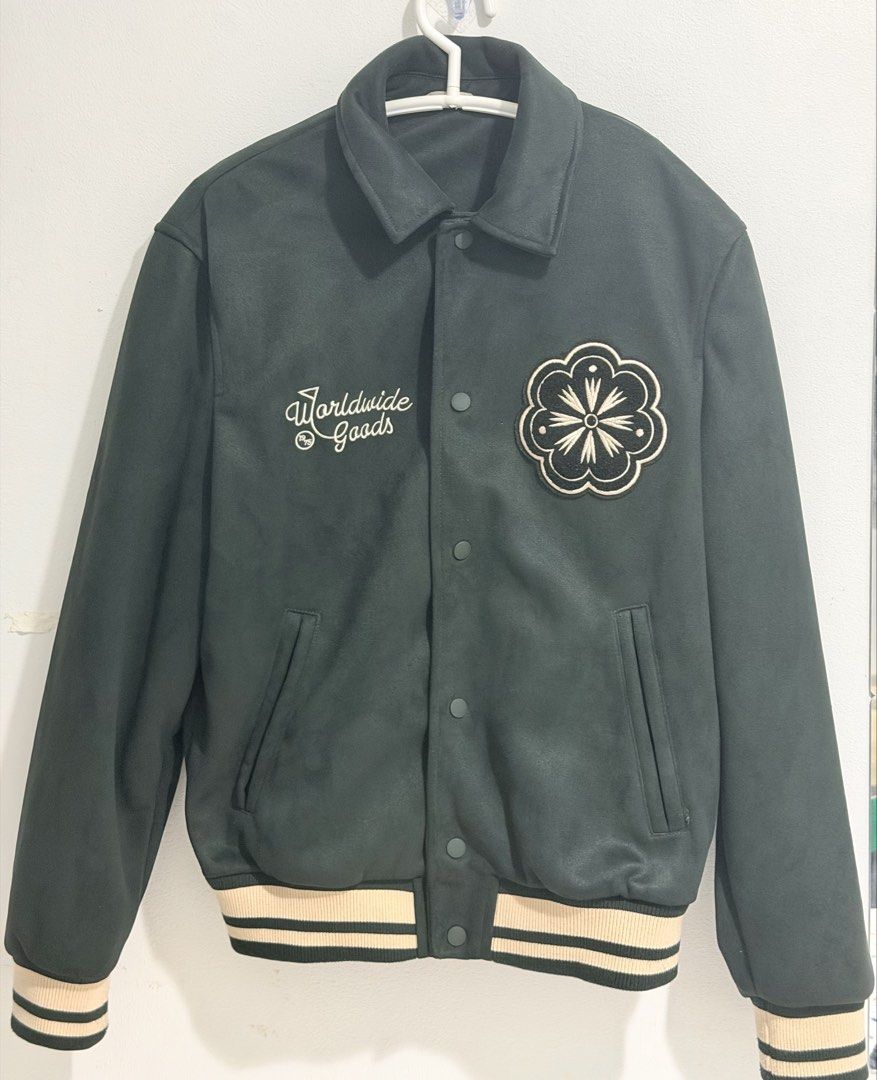 Zara Dark Green Varsity Jacket with Patches (Category: Coats, Jackets and Outerwear) located in Manila. Submitted by aliumcepa (Listing ID 1463677625, Image 1). Description: - Cool dark green varsity jacket - 'Worldwide Goods' embroidered on chest - Floral patch on right side - Ribbed cuffs and hem with cream and black stripes - Button-up front - Two side pockets - Ideal for casual wear.