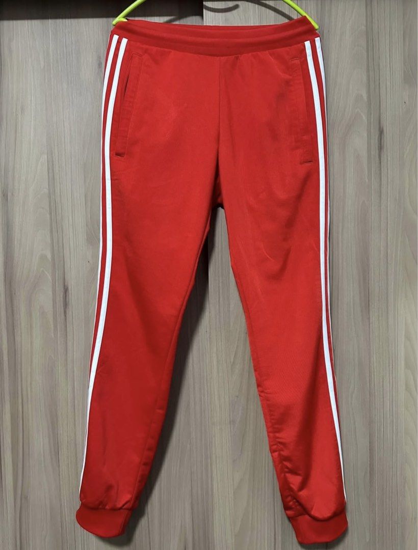 Adidas Red Track Pants with White Stripes (Category: Joggers) located in Paranaque City. Submitted by musikisellerph (Listing ID 1463874490, Image 1). Description: For Sale: ADIDAS ORIGINALS Men’s SST Track Red Pants Size: Small Fits: 28-32 / 175cm height - Classic Adidas track pants in vibrant red - Iconic white three stripes down the sides - Comfortable elastic waistband with drawstring - Cuffed ankles for a snug fit - Versatile for sports or e