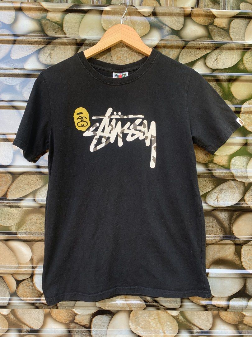 BAPE x Stussy Collaboration Shark Face Tee (Category: Tshirts & Polo Shirts ) located in Aloran. Submitted by chester78864 (Listing ID 1463902863, Image 1). Description: - Authentic Black BAPE x Stussy Collaboration T-Shirt - Size: Medium (M) - Front Design: Iconic Stussy logo with camouflage fill and BAPE ape head graphic - Back Design: Classic BAPE shark face graphic - Condition: Great, perfect for collectors and streetwear enthusiasts.