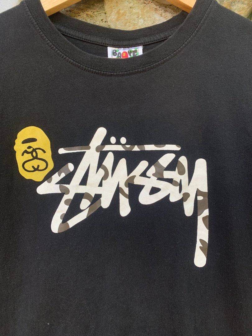 BAPE x Stussy Collaboration Shark Face Tee (Category: Tshirts & Polo Shirts ) located in Aloran. Submitted by chester78864 (Listing ID 1463902863, Image 2). Description: - Authentic Black BAPE x Stussy Collaboration T-Shirt - Size: Medium (M) - Front Design: Iconic Stussy logo with camouflage fill and BAPE ape head graphic - Back Design: Classic BAPE shark face graphic - Condition: Great, perfect for collectors and streetwear enthusiasts.