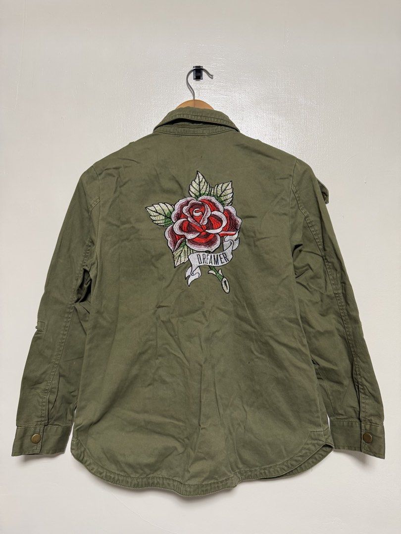 Bershka Olive Green Embroidered Rose Jacket (Category: Coats, Jackets and Outerwear) located in Manila. Submitted by don_p (Listing ID 1463862854, Image 2). Description: S to M - Olive green jacket - Cool rose embroidery on the back - "Dreamer" ribbon detail on the rose - Button-up front - Pockets included - Shoulder epaulets - Button cuffs - Ideal for layering.