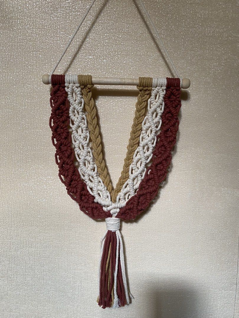 Rush SALE Boho Macrame Wall Hanging Decor (Category: Wall Decor) located in Caloocan City. Submitted by wearprelovedmnl (Listing ID 1463785117, Image 1). Description: - Handmade macrame wall hanging - Features a beautiful layered design - Colors: Maroon, white, and tan cords - Mounted on a wooden dowel - Adds a bohemian touch to any room - Perfect for living rooms, bedrooms, or nurseries - Unique home decor piece.