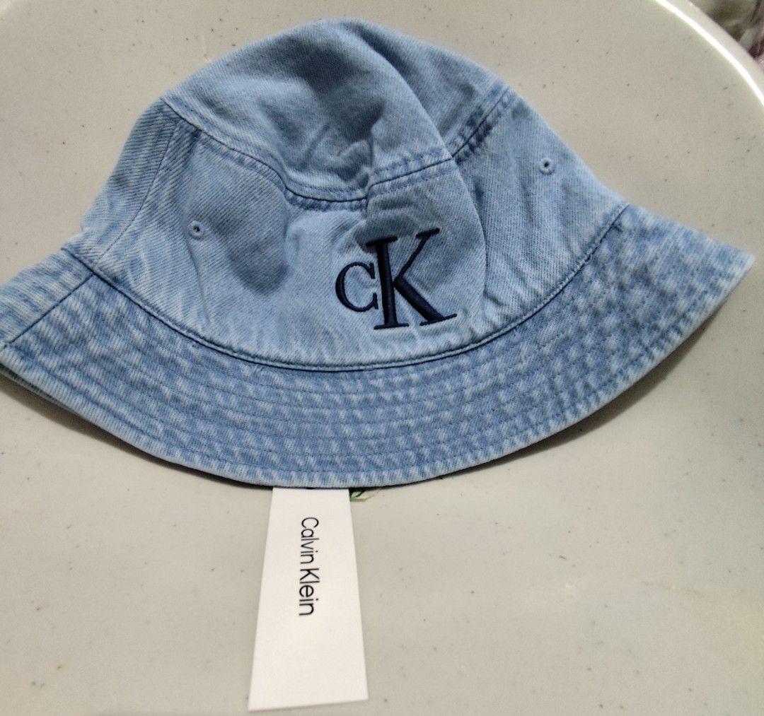 Calvin Klein CK Denim Bucket Hat (Category: Hats & Beanies) located in Imus. Submitted by jmakati22717201 (Listing ID 1463884924, Image 1). Description: - Brand: Calvin Klein - Style: Bucket Hat - Material: Light Wash Denim - Feature: Embroidered iconic CK logo on front - Condition: Brand new with original tag attached - Perfect for sunny days and casual wear.
