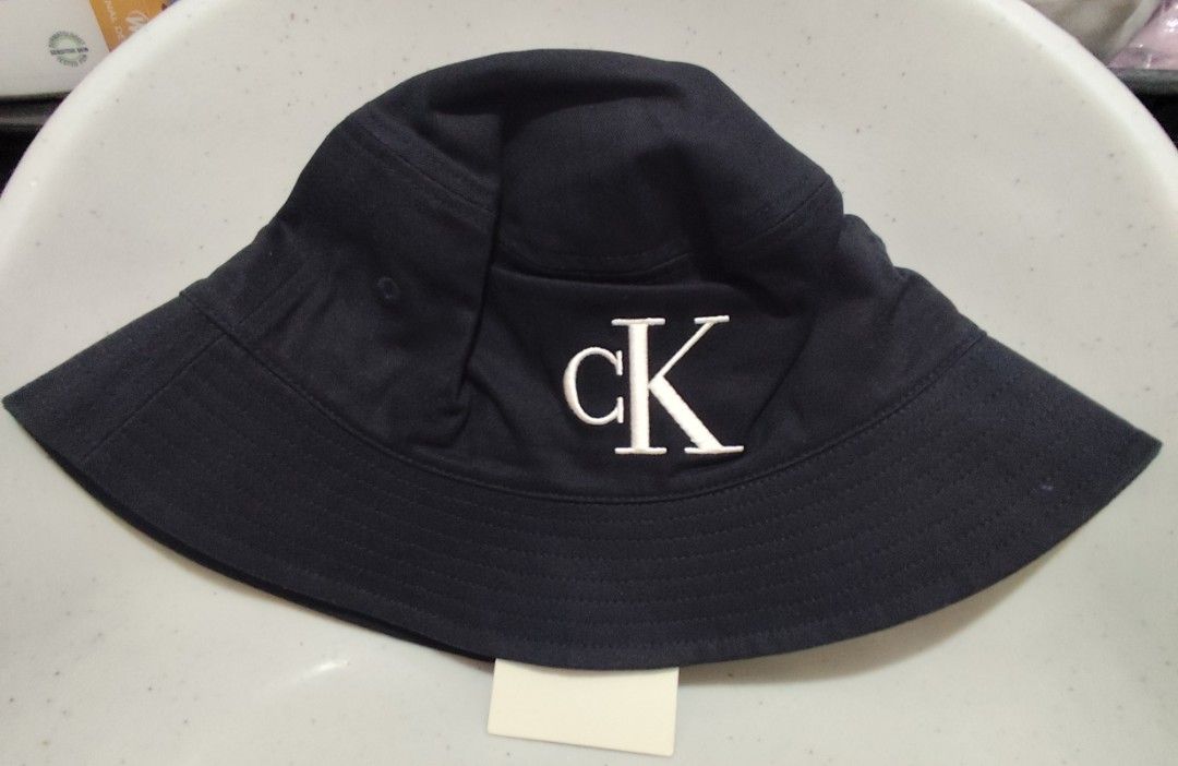 Calvin Klein CK Logo Bucket Hat Navy (Category: Caps & Hats) located in Imus. Submitted by jmakati22717201 (Listing ID 1463884776, Image 1). Description: - Navy blue Calvin Klein bucket hat - Features iconic white CK logo embroidery on front - Classic bucket hat design with wide brim - Perfect for sunny days or casual styling.