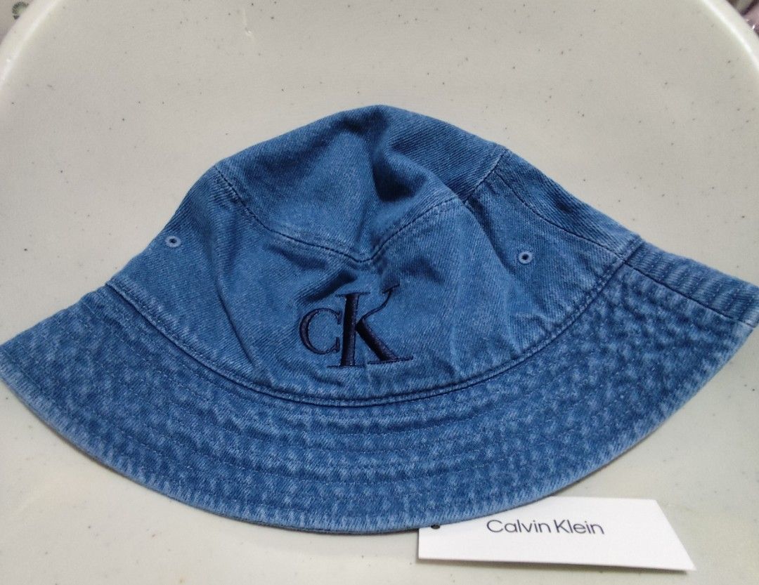 Calvin Klein Denim Bucket Hat (Category: Hats & Beanies) located in Imus. Submitted by jmakati22717201 (Listing ID 1463884706, Image 1). Description: - Classic blue denim bucket hat - Features iconic embroidered CK logo - Versatile accessory for casual outfits - Ideal for sunny days - One size fits most.