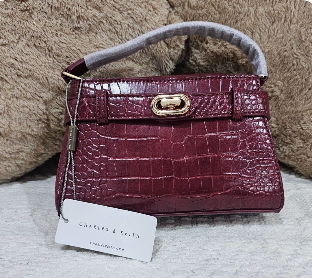 Charles & Keith Burgundy Croc Embossed Top Handle Bag (Category: Tote Bags) located in Manila. Submitted by thriftwitlove (Listing ID 1463796228, Image 1). Description: - Burgundy croc-embossed top handle bag - Brand: Charles & Keith - Features a gold turn-lock closure - Comes with original tag - Perfect for dressing up or down.