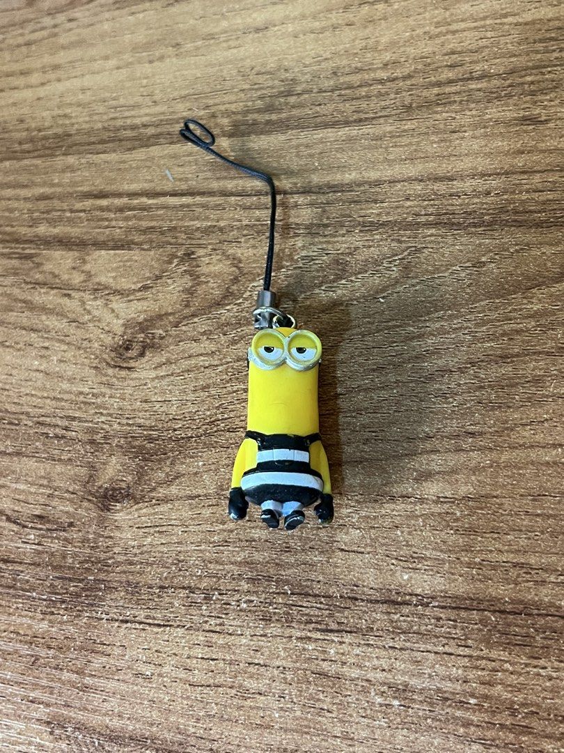 Despicable Me Minion Charm with Strap (Category: Character Goods) located in Gapan. Submitted by lunashop14 (Listing ID 1463749768, Image 1). Description: - Adorable Minion charm from Despicable Me - Features iconic black and white striped outfit - Comes with a convenient black strap and metal clasp - Ideal for personalizing your phone, bag, or keychain - Small and portable accessory for everyday use.