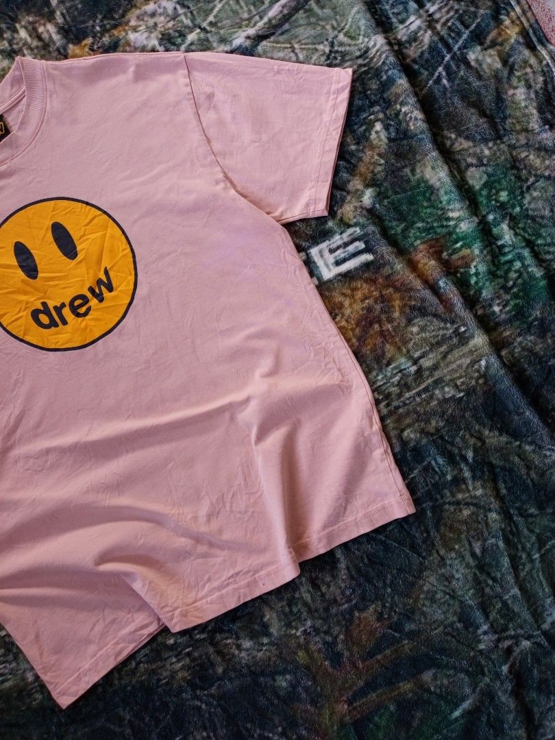 Drew shirt (Category: Tshirts & Polo Shirts ) located in Sugbongcogon. Submitted by yan.drip (Listing ID 1463876983, Image 3). Description: Brand:Drew Housem (founded by Justin Bieber) Style: Mascot Short-Sleeve T-Shirt Color: Dusty Rose / Pale Pink / Light Pink Graphic: Yellow Smiley Face "Mascot" print Fit: Relaxed, oversized streetwear silhouette Features: Ribbed crewneck collar, heavy-grade premium cotton fabric, embroidered/woven brand logo 