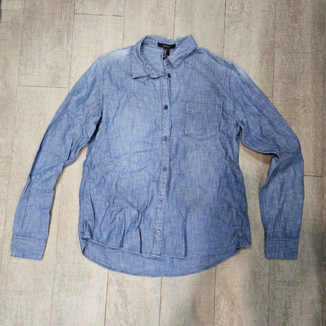 F21 Blue Chambray Long Sleeve Button Up Shirt (Category: Longsleeves) located in Makati City. Submitted by goldenbird.001 (Listing ID 1463867141, Image 1). Description: - Blue chambray shirt from Forever 21 - Long sleeves with button cuffs - Single chest pocket - Button-up front - Ideal for casual wear or layering.
