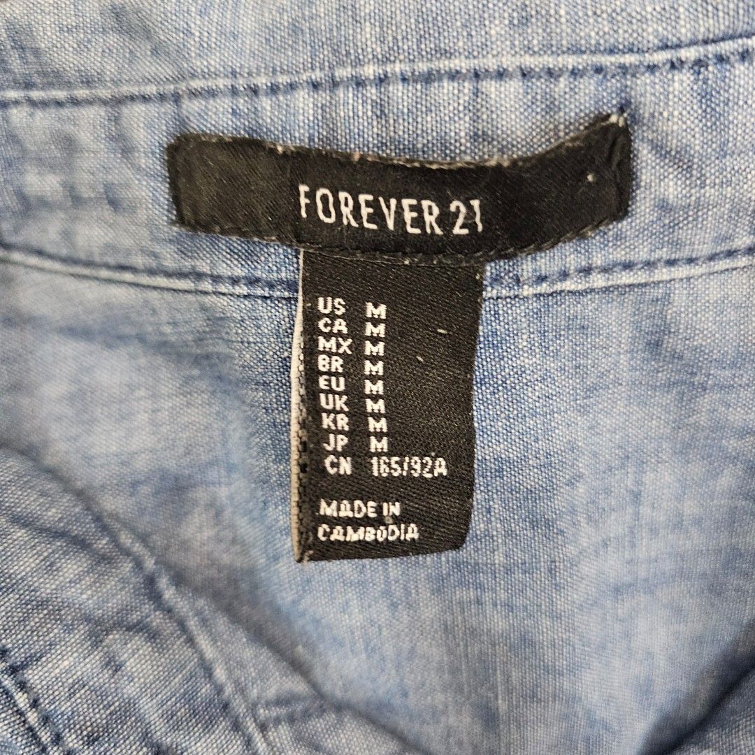 F21 Blue Chambray Long Sleeve Button Up Shirt (Category: Longsleeves) located in Makati City. Submitted by goldenbird.001 (Listing ID 1463867141, Image 2). Description: - Blue chambray shirt from Forever 21 - Long sleeves with button cuffs - Single chest pocket - Button-up front - Ideal for casual wear or layering.