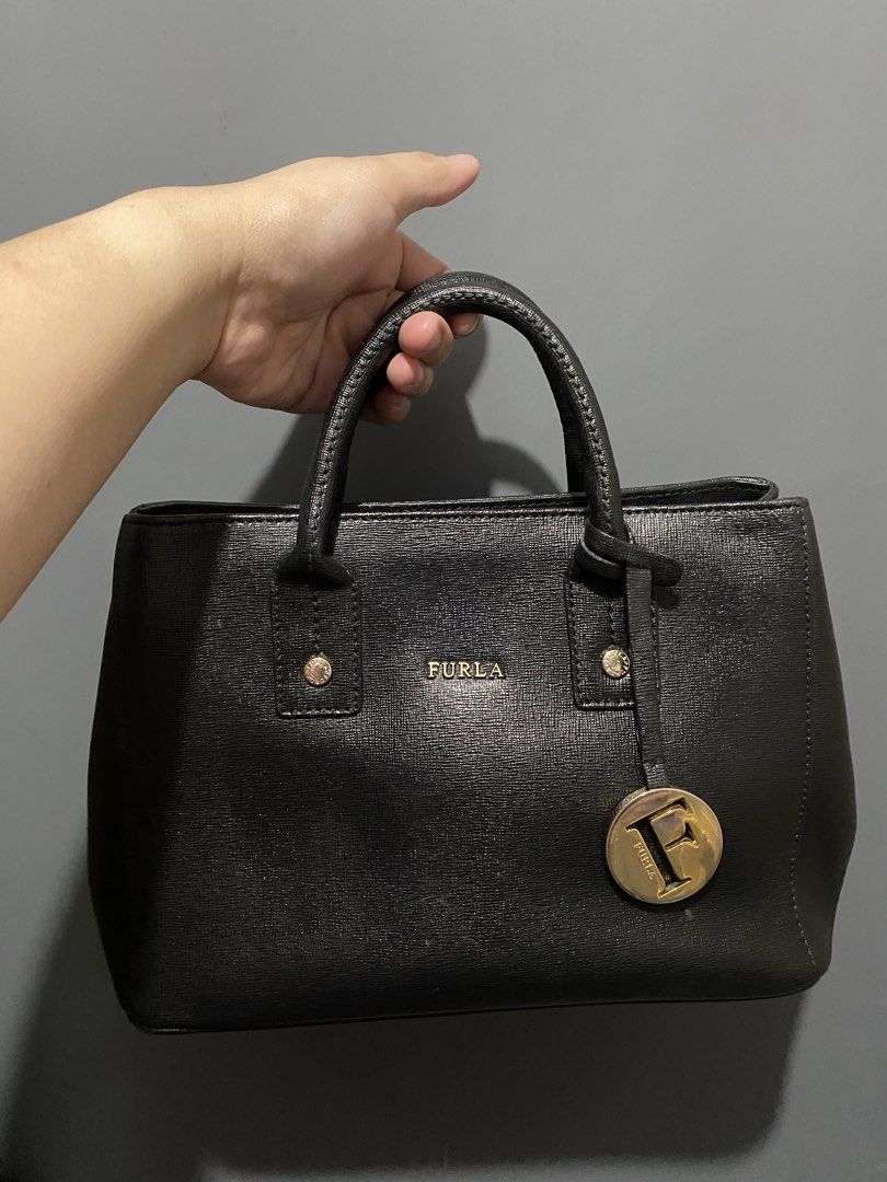 Furla Black Leather Tote Bag (Category: Luxury Bags & Wallets) located in Batangas. Submitted by bagstolove3.0 (Listing ID 1463901053, Image 1). Description: - Classic black Furla leather bag. - Textured leather finish for a sophisticated look. - Elegant gold hardware, including the iconic Furla logo charm. - Comfortable top handles for easy carrying. - Structured design with protective metal feet on the bottom. - An ideal and stylish everyday ba
