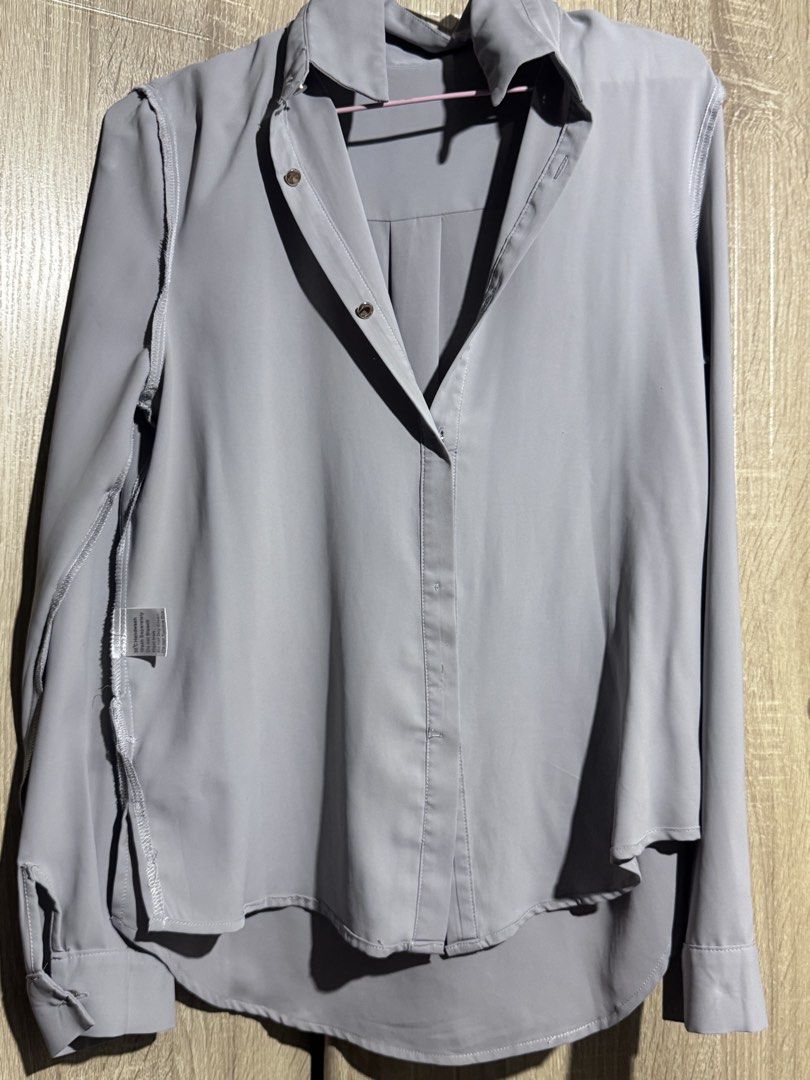 Grey Button-Up Shirt (Category: Shirts) located in Mandaluyong City. Submitted by santamaria505 (Listing ID 1463824064, Image 1). Description: - Light grey button-up shirt - Relaxed fit with a slightly longer hem at the back - Made from light and flowy material - Versatile for casual or work wear - Effortless to style.