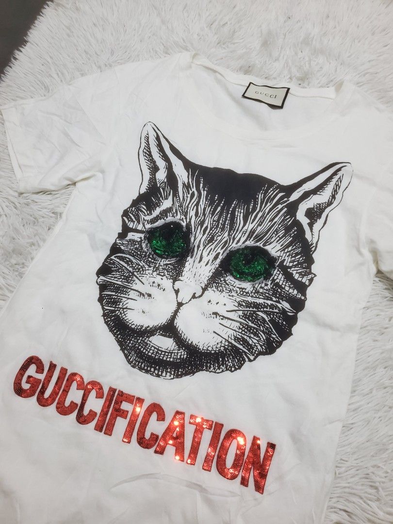 Gucci Cat Print T-Shirt (Category: Shirts) located in Manila. Submitted by royalrabbit.7b2a11 (Listing ID 1463895744, Image 2). Description: - White Gucci T-Shirt - Size: XS - Design: Graphic cat print with "GUCCIFICATION" text - Features: Iconic Gucci logo tag - Style: Ideal for casual wear - Condition: Great.