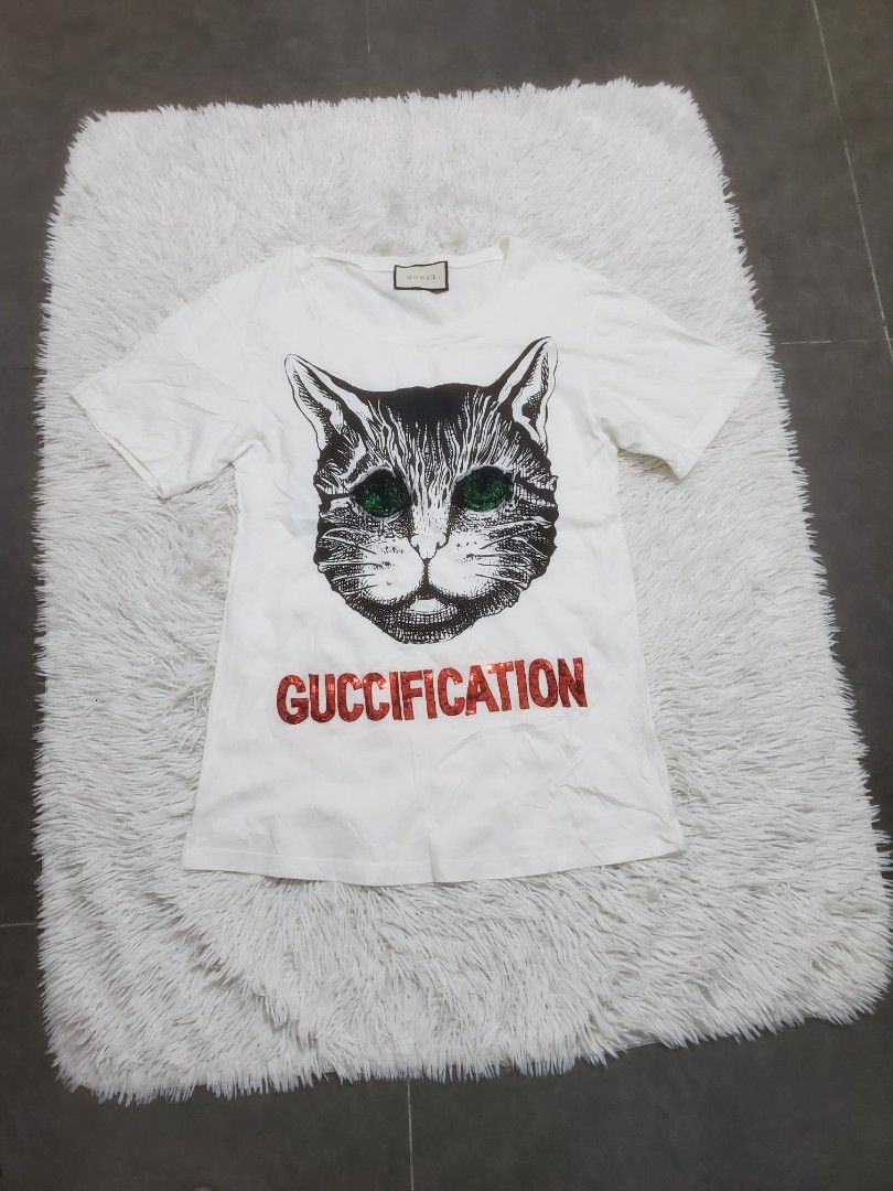 Gucci Cat Print T-Shirt (Category: Shirts) located in Manila. Submitted by royalrabbit.7b2a11 (Listing ID 1463895744, Image 1). Description: - White Gucci T-Shirt - Size: XS - Design: Graphic cat print with "GUCCIFICATION" text - Features: Iconic Gucci logo tag - Style: Ideal for casual wear - Condition: Great.