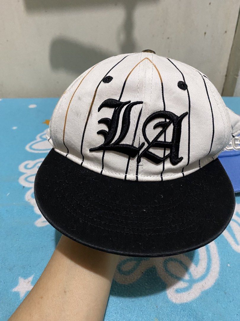 H&M LA Cap & Yankees Visor Bundle (Category: Babies & Kids Fashion) located in Manila. Submitted by resi.diaz (Listing ID 1463838050, Image 2). Description: - 6-8 years old - Bundle includes 2 headwear items: - H&M Cap: White with black pinstripes, 'LA' design, black brim, adjustable strap. - New York Yankees Visor: Blue and grey colorway. - Both are great for casual outings or showing team spirit..