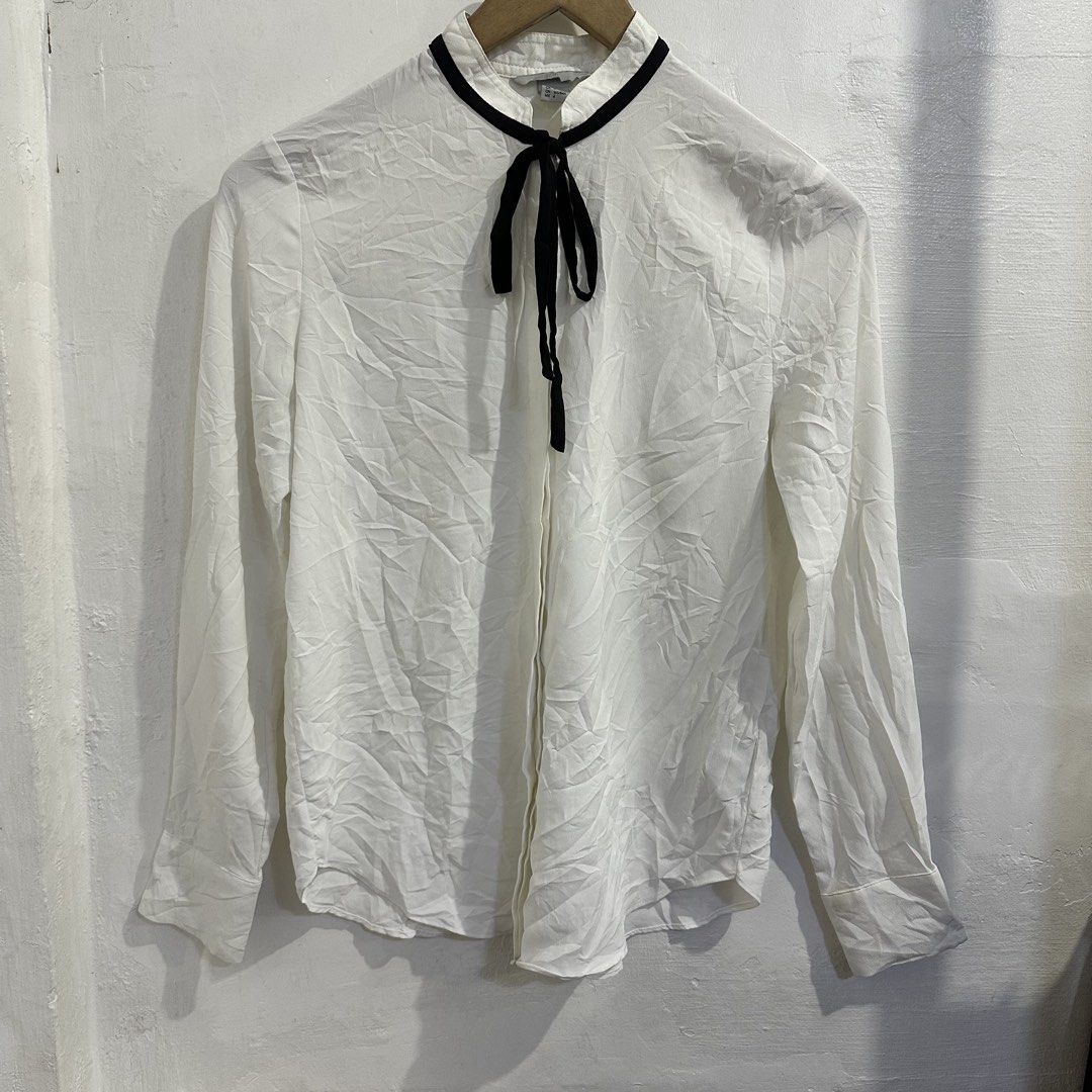 H&M White Long Sleeve Bow Blouse (Category: Longsleeves) located in San Jose del Monte. Submitted by bizzybeebyhgc (Listing ID 1463828570, Image 1). Description: - Brand: H&M - Color: White - Style: Long-sleeved blouse - Features: Black ribbon tie at neck, button-up front, buttoned cuffs - Material: 100% Polyester - Estimated Size: US 4 / EUR 36 - Versatile: Perfect for dressing up or down.