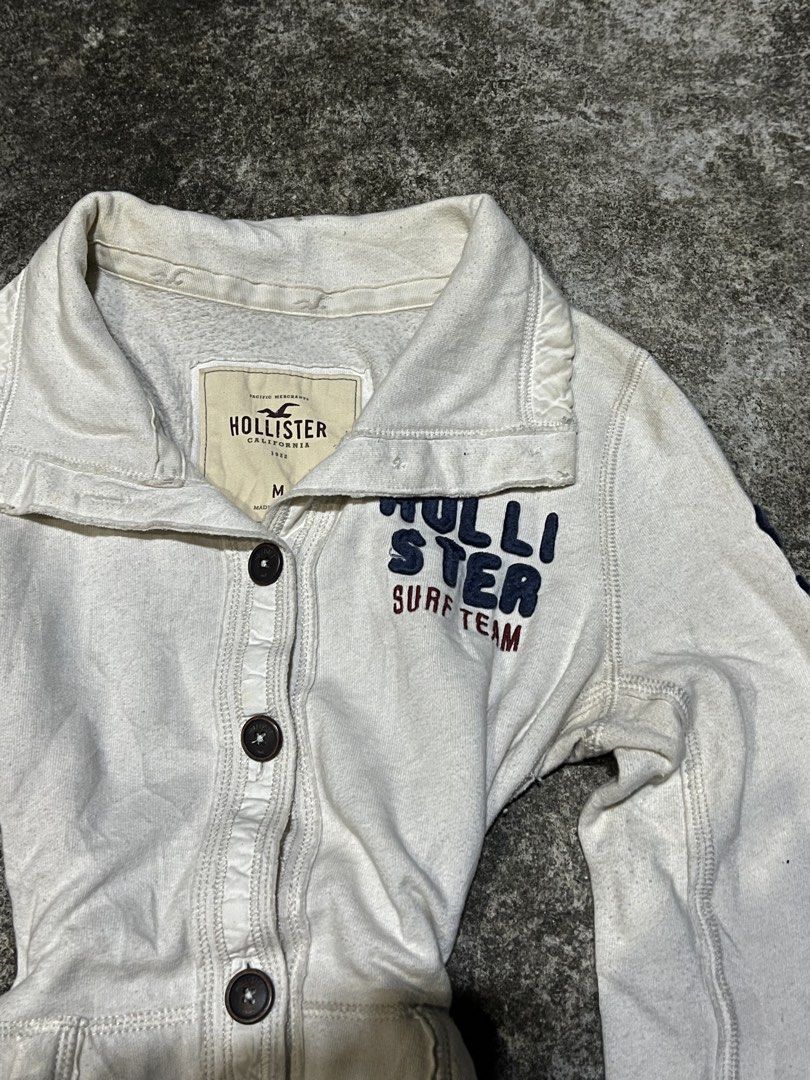 Hollister Surf Team White Button Up Jacket Size M (Category: Coats, Jackets and Outerwear) located in San Isidro, Leyte. Submitted by tigerxdx3580077 (Listing ID 1463880886, Image 2). Description: - White Hollister jacket - 'Hollister Surf Team' graphic - Button-up front - Collared neckline - Long sleeves with ribbed cuffs - Size: Medium (M) - Ideal for casual wear.