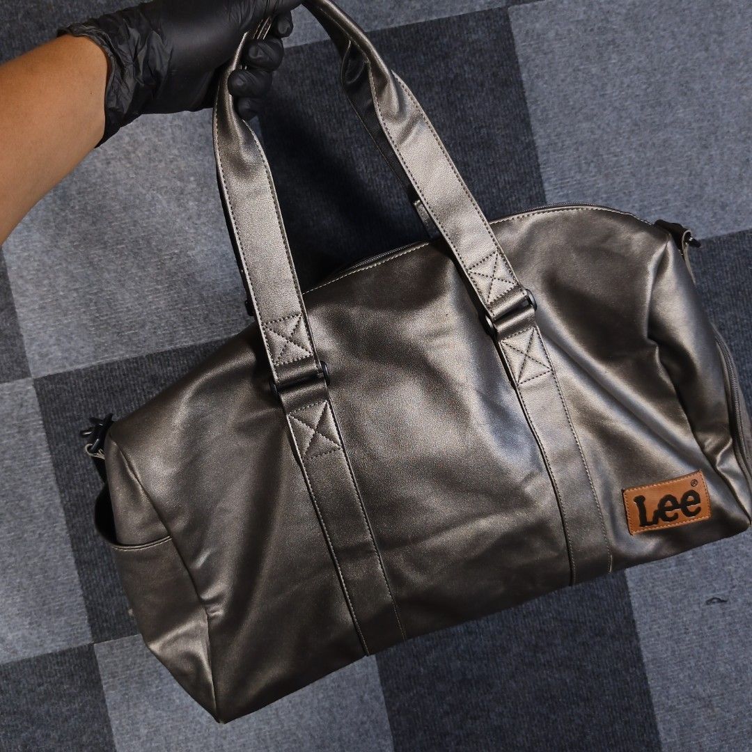 Lee Company Metallic Grey Duffle Bag (Category: Sling Bags) located in Tagum. Submitted by kitlowisthrift (Listing ID 1463871724, Image 3). Description: - Metallic grey duffle bag by Lee Company - Main compartment with secure zipper closure - Convenient side pocket with zipper - Adjustable strap featuring repeating 'Lee Company' print - Ideal for gym sessions or weekend getaways.