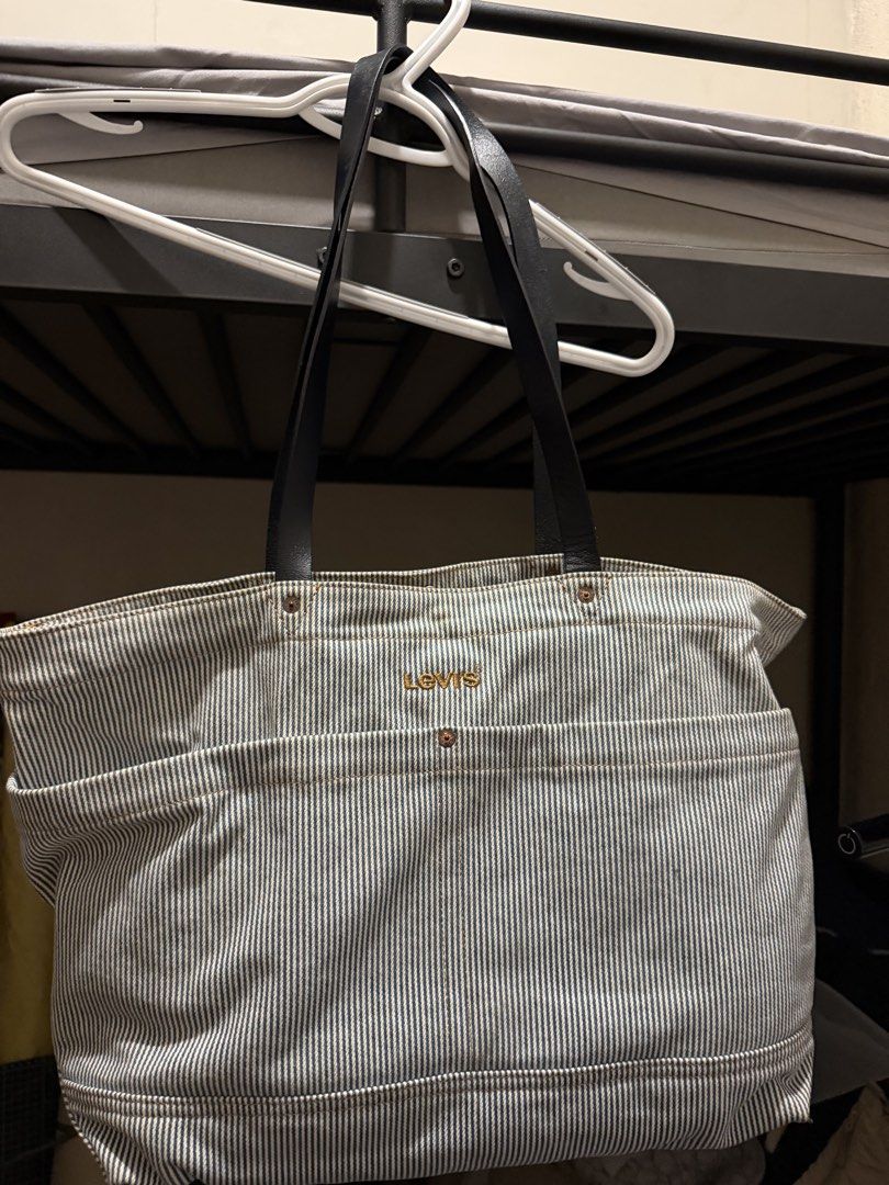 Levi's Striped Denim Tote Bag (Category: Tote Bags) located in Iloilo. Submitted by juca.sale (Listing ID 1463877787, Image 1). Description: - Classic Levi's tote bag - Blue and white pinstripe denim material - Black leather straps - Multiple exterior pockets for easy access - Interior pocket with branded Levi's tag - Spacious and durable design - Perfect for everyday use or travel.