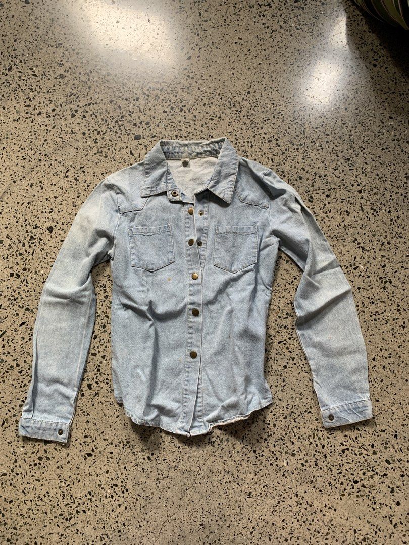 Light Wash Denim Button-Up Shirt (Category: Blouses) located in Quezon City. Submitted by p.j.c.a.r.o.u.s.e.l.l.i.n.g (Listing ID 1463787318, Image 1). Description: - Classic light wash denim shirt - Long sleeves with button cuffs - Two chest pockets with button closures - Button-up front - Versatile for layering or wearing solo.