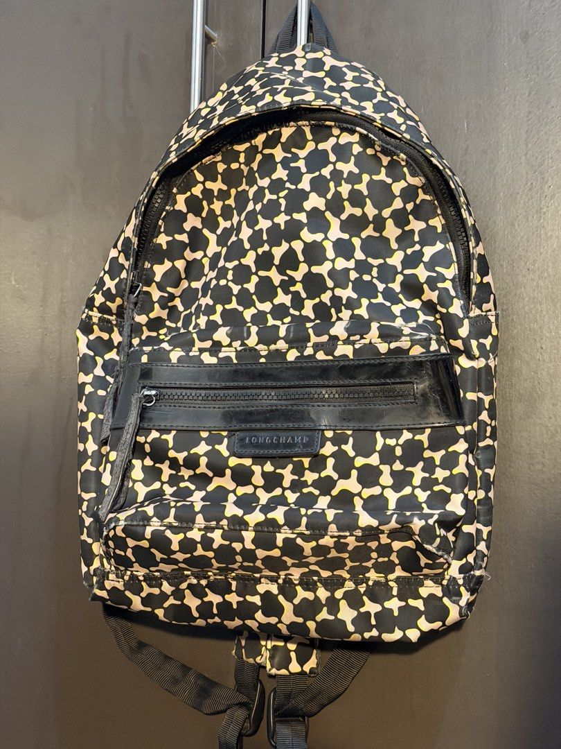 Longchamp Backpack (Category: Backpacks) located in Manila. Submitted by jlcvinci (Listing ID 1463879939, Image 1). Description: - Stylish camo print backpack from Longchamp - Color: Black, beige, and yellow pattern - Features a front zip pocket with leather trim - Note: Zipper pull on front pocket is slightly worn - Fraying on side seam near zipper - Still a functional and great bag for daily use.