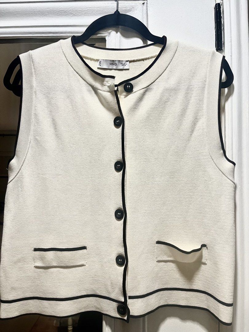 MANGO Cream Knit Vest with Black Trim (Category: Sleeveless) located in Pasig City. Submitted by thestoragestudio (Listing ID 1463812695, Image 1). Description: - Cream knit vest from Mango - Size: Medium - Black trim accents on neckline, armholes, and hem - Two front pockets with black trim - Button-up front with black buttons - Made in Turkey.