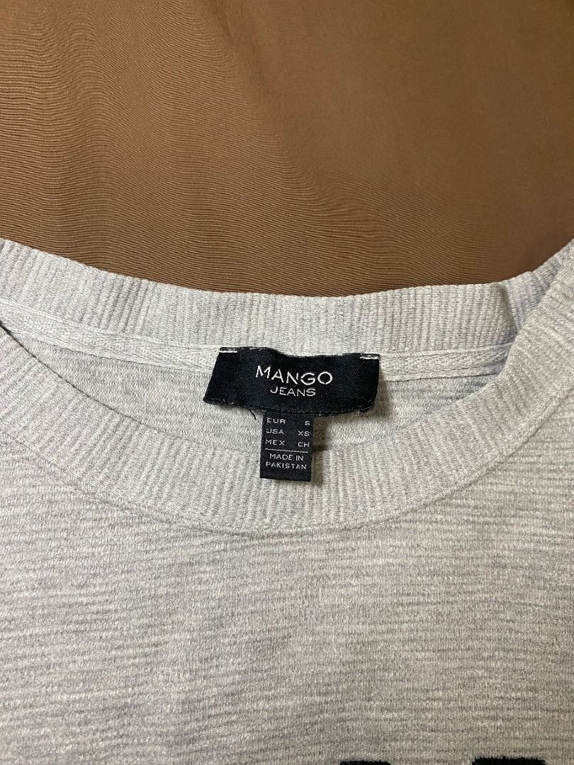 Mango Jeans Grey 'Ciao Bella' Sweater (Category: Longsleeves) located in San Pablo. Submitted by kisha_santonia (Listing ID 1463871008, Image 3). Description: - Grey sweater from Mango Jeans - Features 'Ciao Bella' text on the front - Side zippers for added style and adjustability - Ribbed texture throughout for a cozy feel - Size: Small (S).