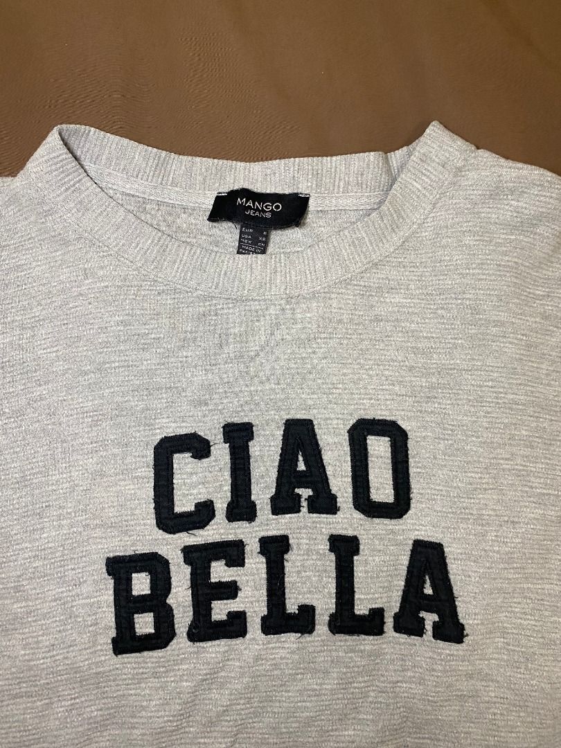 Mango Jeans Grey 'Ciao Bella' Sweater (Category: Longsleeves) located in San Pablo. Submitted by kisha_santonia (Listing ID 1463871008, Image 2). Description: - Grey sweater from Mango Jeans - Features 'Ciao Bella' text on the front - Side zippers for added style and adjustability - Ribbed texture throughout for a cozy feel - Size: Small (S).