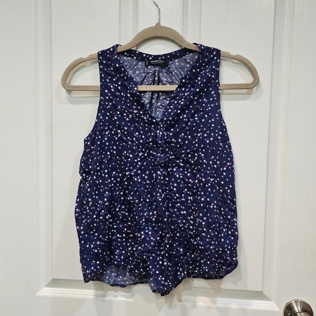 Mango Navy Star Print Sleeveless Top (Category: Sleeveless) located in Makati City. Submitted by goldenbird.001 (Listing ID 1463842541, Image 1). Description: - Navy blue sleeveless top - White and red star print - V-neck design - Ruched detail at the front - Lightweight fabric, ideal for warm weather - Versatile for dressing up or down.