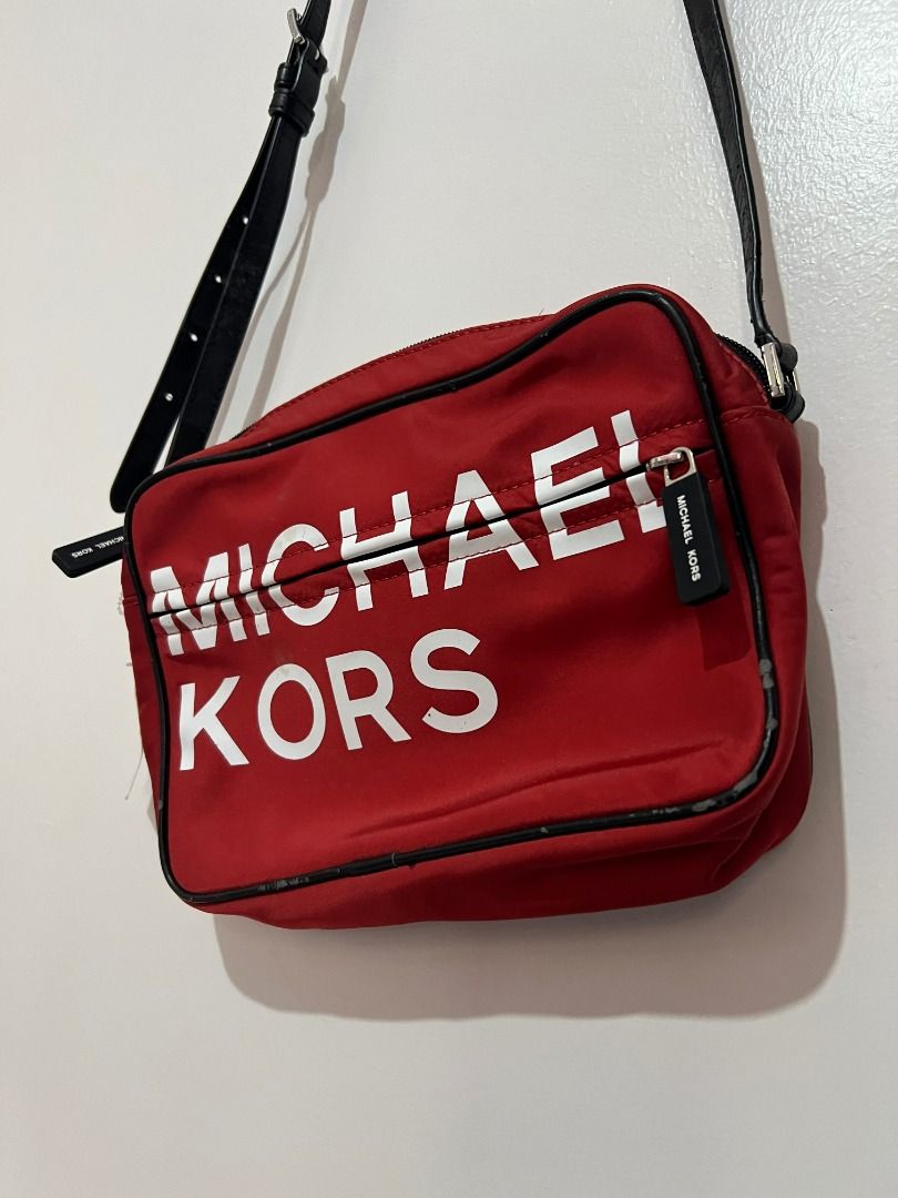 Michael Kors Red Nylon Crossbody Bag (Category: Cross-body Bags) located in Davao. Submitted by jpnusapasabuyfindsdvo (Listing ID 1463901949, Image 3). Description: - NEVER USED WITH A TAG, BOUGHT FROM US. - Red Michael Kors crossbody bag - Durable nylon material with black trim - Features a large white Michael Kors logo on the front - Secure zipper closure - Adjustable strap for comfortable wear - Ideal for everyday use - Spacious interior for y