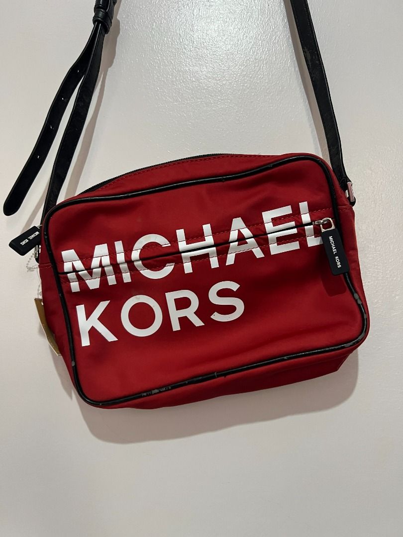 Michael Kors Red Nylon Crossbody Bag (Category: Cross-body Bags) located in Davao. Submitted by jpnusapasabuyfindsdvo (Listing ID 1463901949, Image 2). Description: - NEVER USED WITH A TAG, BOUGHT FROM US. - Red Michael Kors crossbody bag - Durable nylon material with black trim - Features a large white Michael Kors logo on the front - Secure zipper closure - Adjustable strap for comfortable wear - Ideal for everyday use - Spacious interior for y