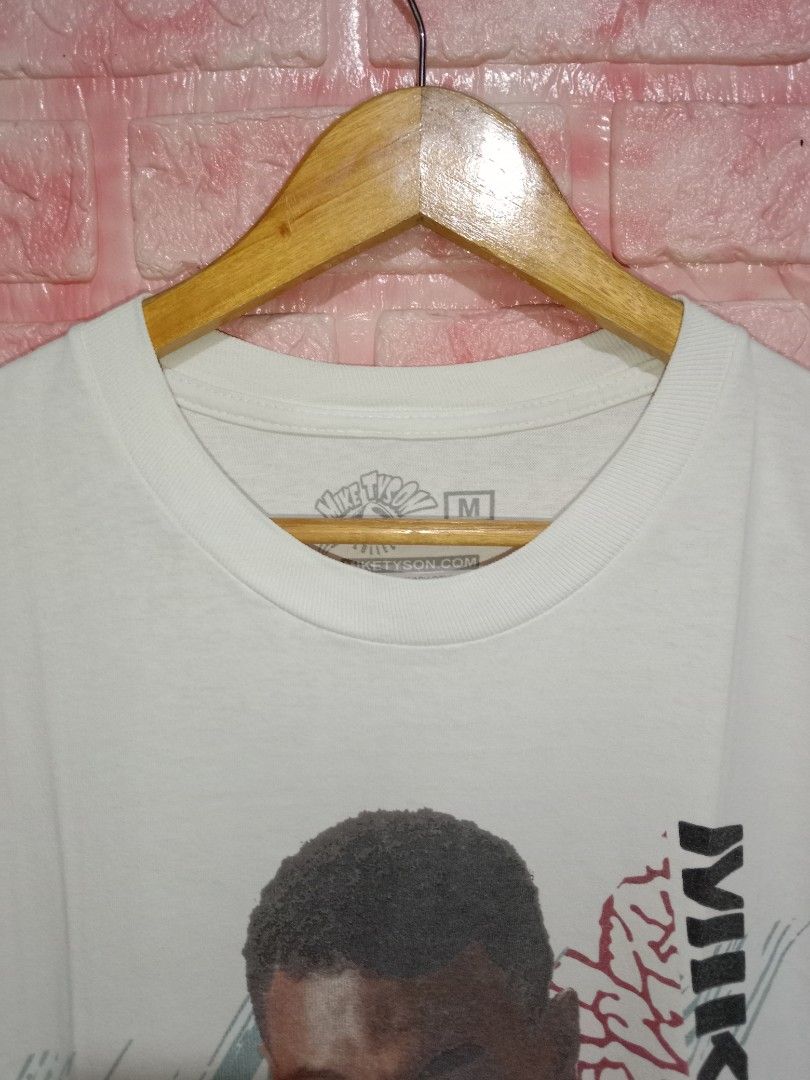 Mike Tyson Power Puncher Merch (Category: Tshirts & Polo Shirts ) located in Davao. Submitted by ayeeasyshop13 (Listing ID 1463891421, Image 2). Description: This is a white Mike Tyson graphic t-shirt featuring a vintage boxing portrait of the athlete alongside bold vertical typography and gold script lettering. Verygood condition Issue pinhole see on last pic Size medium on tag Dimension 20/28 450 + SF.