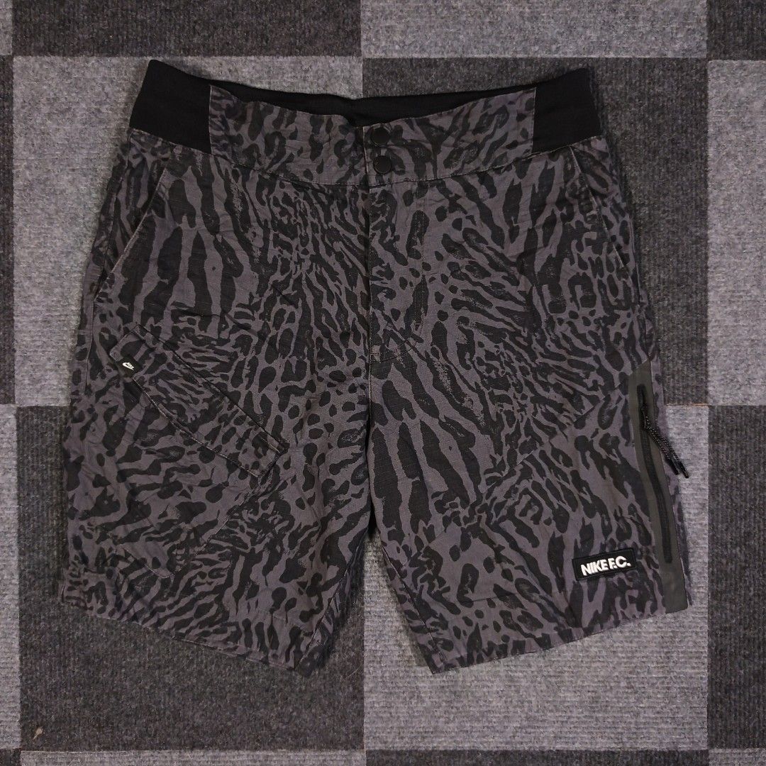 Nike F.C. Shorts Size M - Grey Camo Pattern (Category: Shorts) located in Tagum. Submitted by kitlowisthrift (Listing ID 1463871719, Image 1). Description: - Nike F.C. shorts - Size: Medium (M) - Color: Cool grey and black camouflage print - Features: Pockets, side zip pocket - Waistband: Elastic for comfort - Ideal for: Casual wear or sports activities - Origin: Made in China.