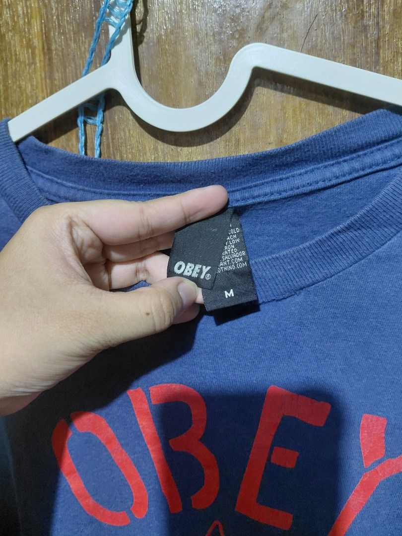 OBEY Graphic T-Shirt Blue Red Eagle Logo Size M (Category: Tshirts & Polo Shirts ) located in Imus. Submitted by frootiloots4103 (Listing ID 1463756087, Image 2). Description: - Blue OBEY graphic t-shirt - Size Medium (M) - Features a striking red eagle and anchor design - Shows minor signs of wear, including a small sticker on the sleeve - A cool addition to any streetwear collection.