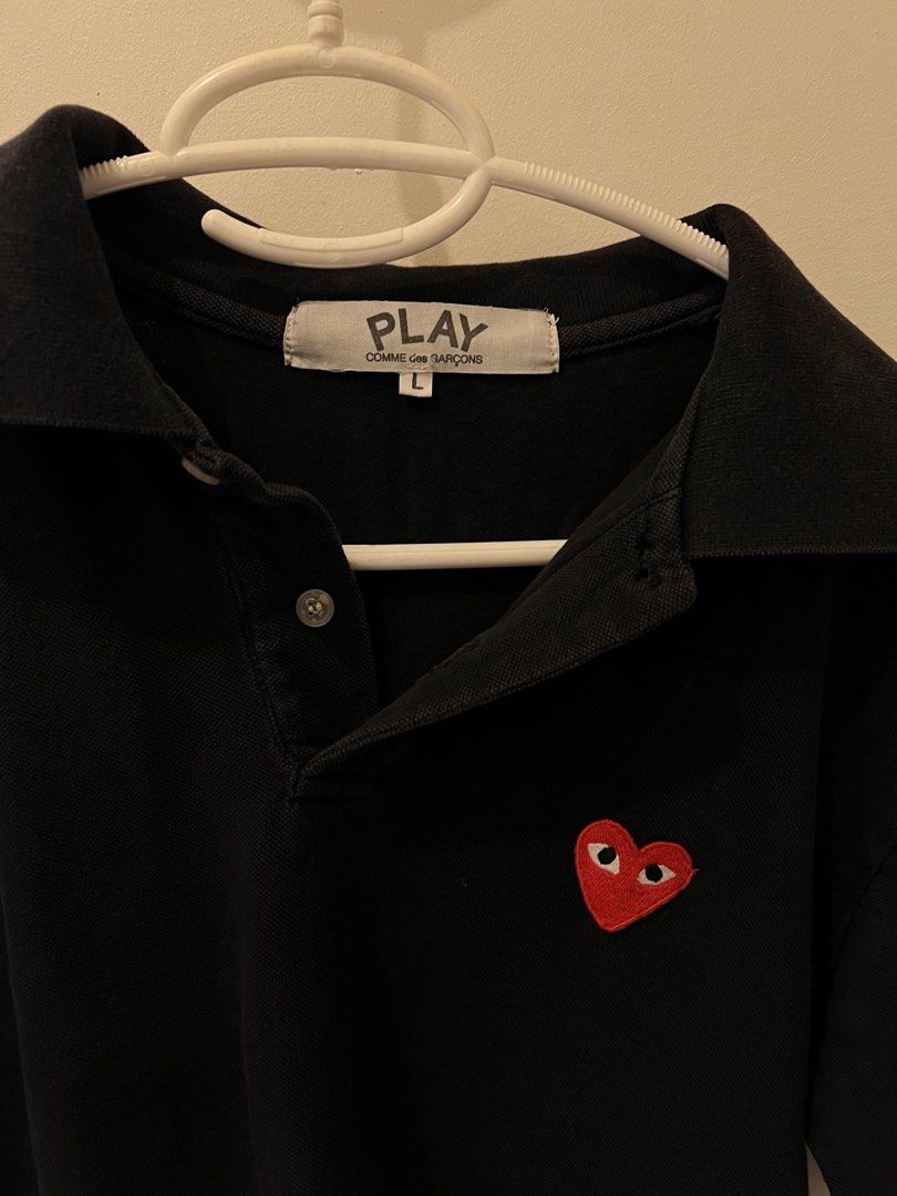 Authentic Comme des Garcons Polo Shirt (Category: Tshirts & Polo Shirts ) located in Las Pinas. Submitted by basicapparel_mnl (Listing ID 1463814604, Image 2). Description: - Brand: PLAY COMME des GARÇONS - check tags for authenticity - Color: Black - Size: L - Feature: Iconic red heart logo on chest - Style: Classic polo collar and button placket - Occasion: Casual wear, layering - Condition: Please check photos for details.