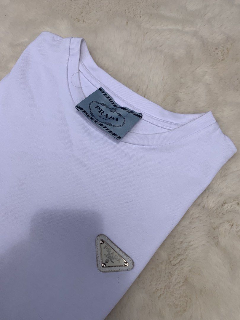 Prada White T-Shirt with Triangle Logo (Category: Formal Shirts) located in Cateel. Submitted by janicegpad45049 (Listing ID 1463880024, Image 2). Description: - Authentic White Prada T-Shirt - Iconic Prada Triangle Logo on Chest - Size: Medium (M) - Made in Romania - Excellent staple piece for any wardrobe - Check tags for further details.