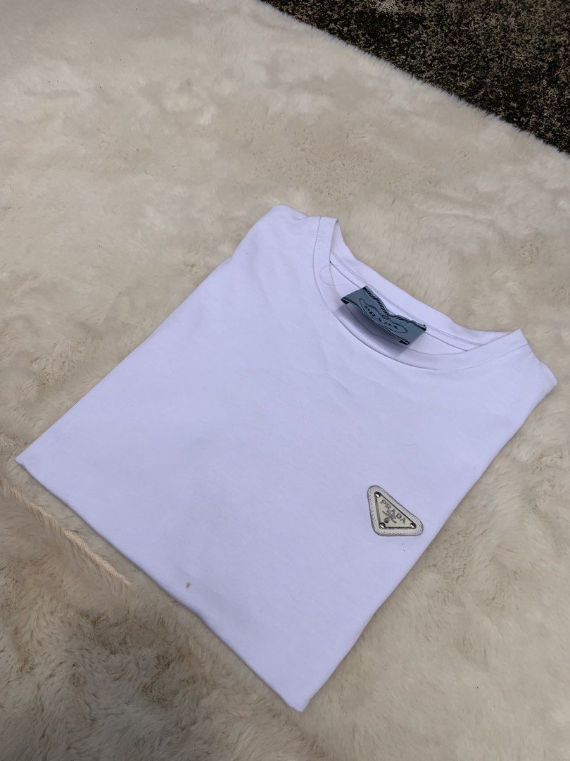 Prada White T-Shirt with Triangle Logo (Category: Formal Shirts) located in Cateel. Submitted by janicegpad45049 (Listing ID 1463880024, Image 1). Description: - Authentic White Prada T-Shirt - Iconic Prada Triangle Logo on Chest - Size: Medium (M) - Made in Romania - Excellent staple piece for any wardrobe - Check tags for further details.