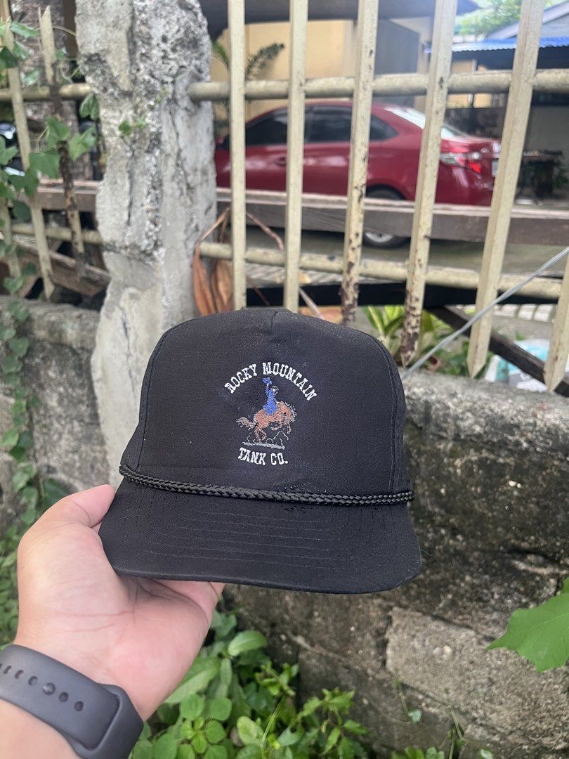 Rocky Mountain Tank Co. Black Snapback Cap (Category: Caps & Hats) located in Manila. Submitted by christian048 (Listing ID 1463834031, Image 1). Description: - Brand: Rocky Mountain Tank Co. - Color: Black - Style: Snapback cap By Youngan - Design: Embroidered logo featuring a cowboy riding a horse - Detail: Rope accent across the brim - Fit: Adjustable strap at the back, one size fits all - Occasion: Ideal for casual wear.
