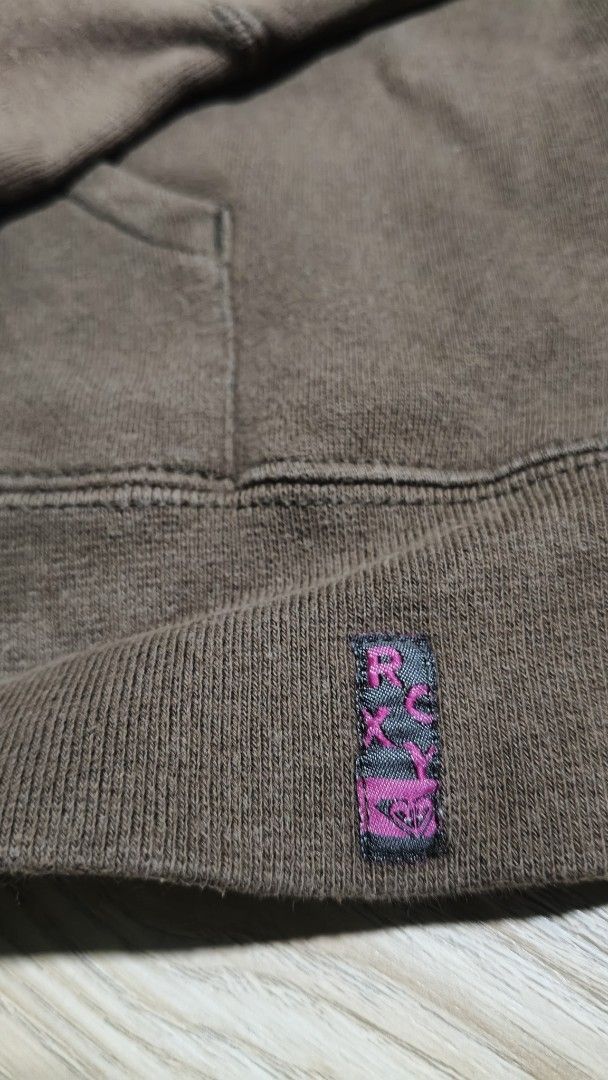 Roxy Brown Hoodie with Striped Design (Category: Coats, Jackets and Outerwear) located in Manila. Submitted by moneyroll420 (Listing ID 1463765895, Image 3). Description: - Brown Roxy hoodie - Diagonal stripe design across the chest in orange, pink, and yellow - Front kangaroo pocket - Made from a cotton and polyester blend - Ideal for casual wear.