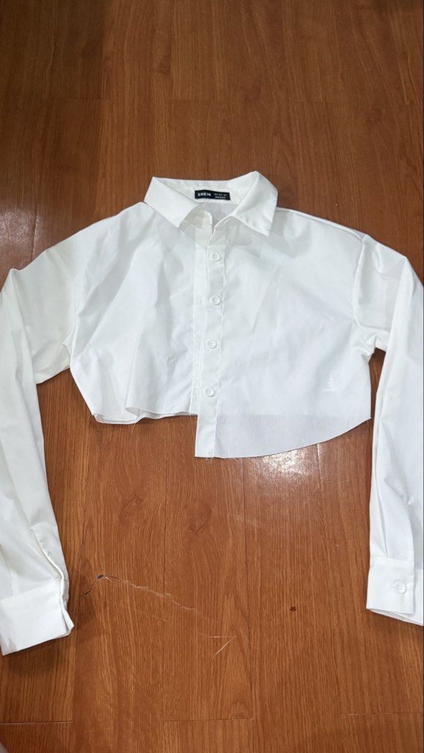 SHEIN White Cropped Button-Up Shirt Size S (Category: Shirts) located in Antipolo. Submitted by japanese.siomai (Listing ID 1463795924, Image 1). Description: - White cropped shirt from SHEIN - Size S - Button-up front with collar - Long sleeves with button cuffs - Raw hem detail - Versatile for layering or wearing solo.