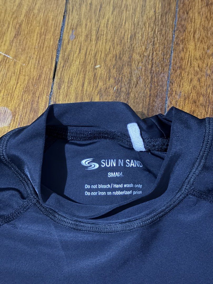 Sun N Sand Long Sleeve Rash Guard (Category: Rash guard) located in Paranaque City. Submitted by declutternsell.729 (Listing ID 1463776059, Image 3). Description: - Brand: Sun N Sand - Color: Black - Style: Long sleeve rash guard - Design: Tribal-inspired patterned panels on sides - Use: Ideal for swimming and sun protection - Care Instructions: Hand wash only - Important Note: Do not iron on rubberized print.